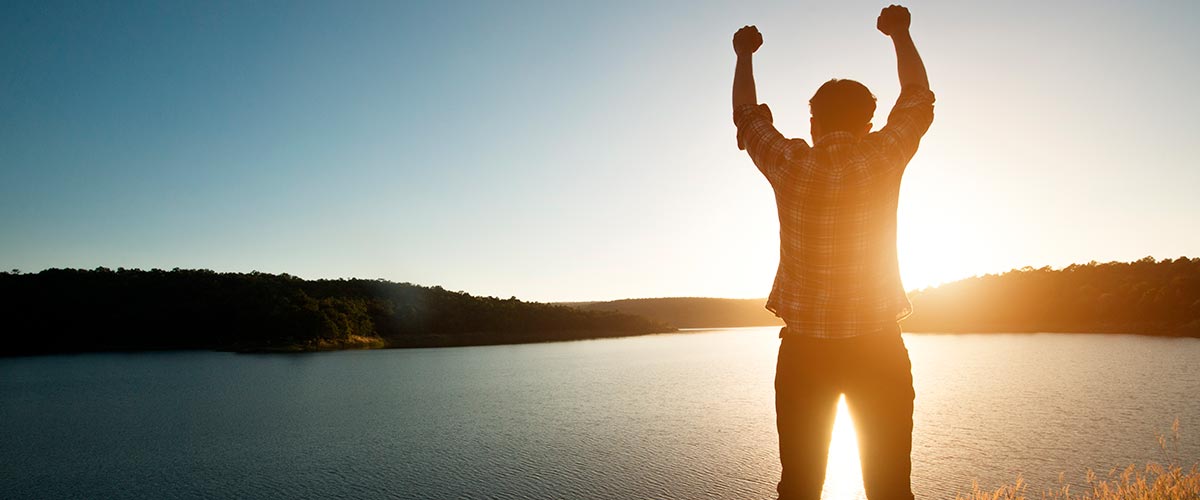 Persona subiendo una montana o con los brazos abiertos reflejando superacion personal.